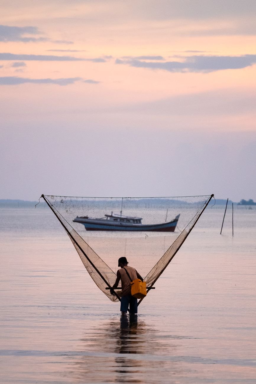 A fisherman casts his net at sunrise in the waters of Bangka Belitung Islands, Indonesia.